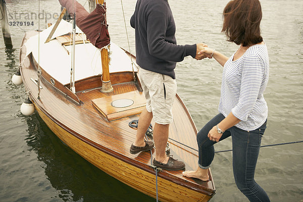 Mann hilft Frau auf altes Boot