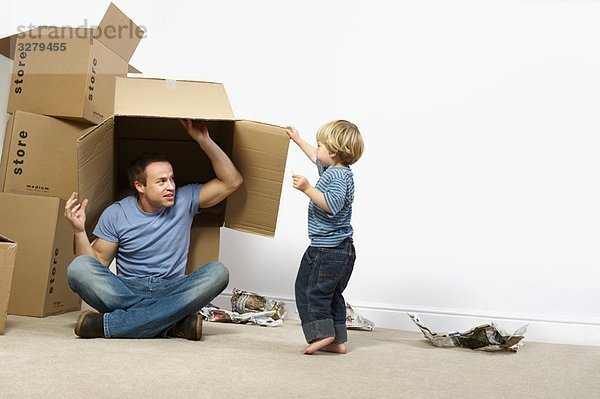 Vater und Sohn spielen mit Umzugskartons