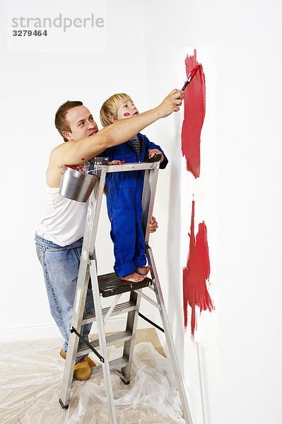 Mann und Kleinkind Junge malen Wand rot