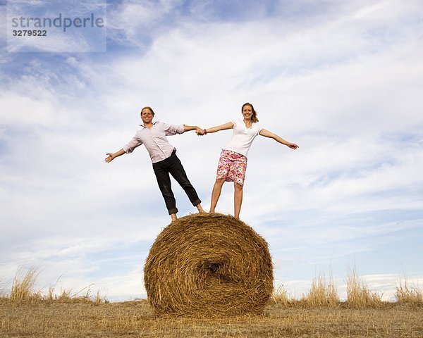 Frau und Mann auf Heuballen stehend