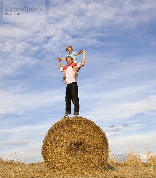 Mann und Junge auf Heuballen stehend