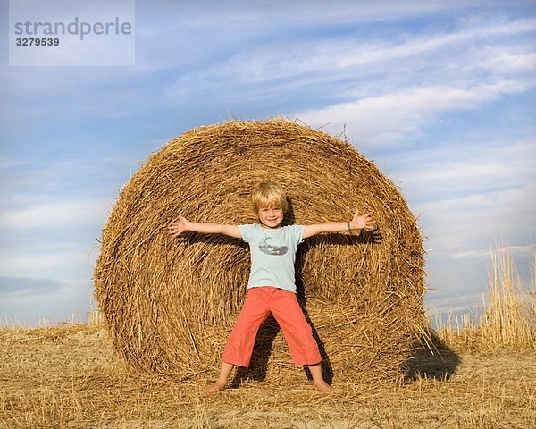 Junge steht vor dem Heuballen