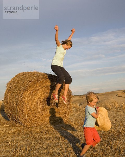 Mädchen und Junge mit Heuballen