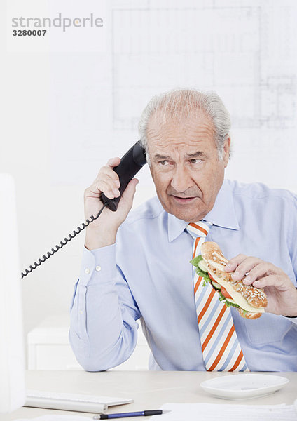 Mann beim Essen am Telefon