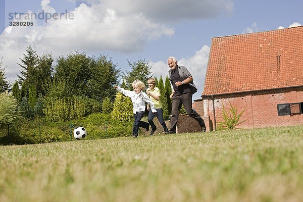 Großvater und Kinder beim Fußballspielen