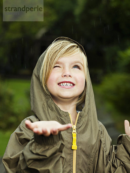 Mädchen hält ihre Hand aus  um Regen zu fangen.