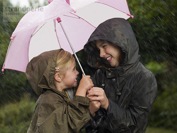 Mädchen unter einem Schirm zusammengekauert