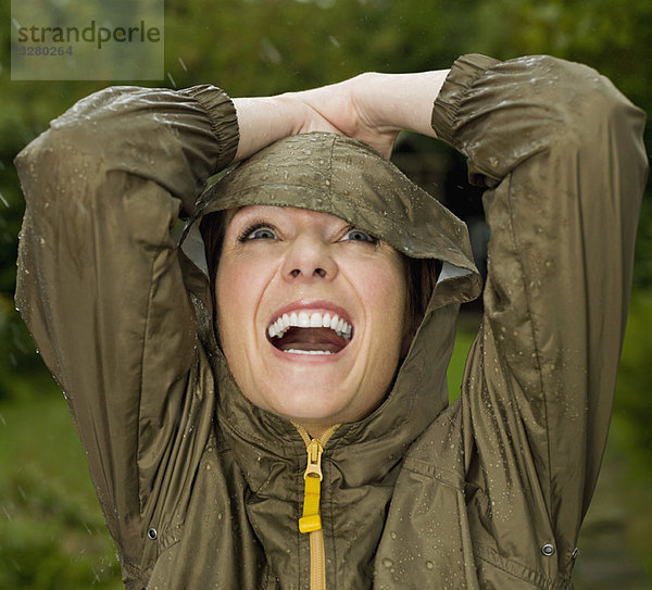 Eine Frau mit erhobenen Armen im Regen.