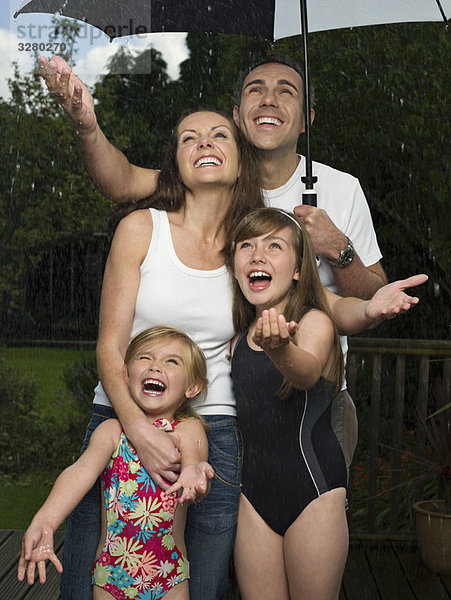 Eine Familie unter dem Schirm im Regen