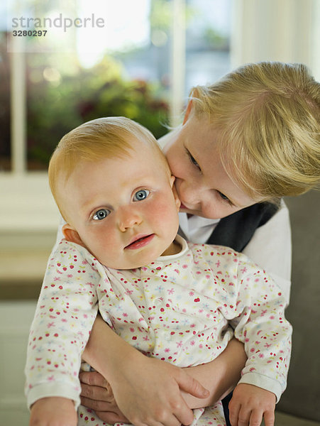 Ein kleines Mädchen  das seine kleine Schwester umarmt.