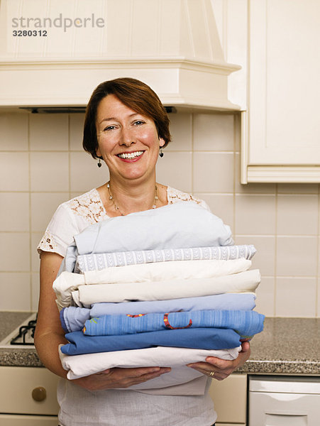 Frau mit einem Haufen gebügelter Wäsche
