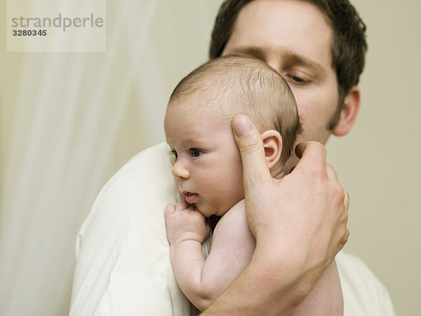 Ein Vater hält sein neugeborenes Baby.