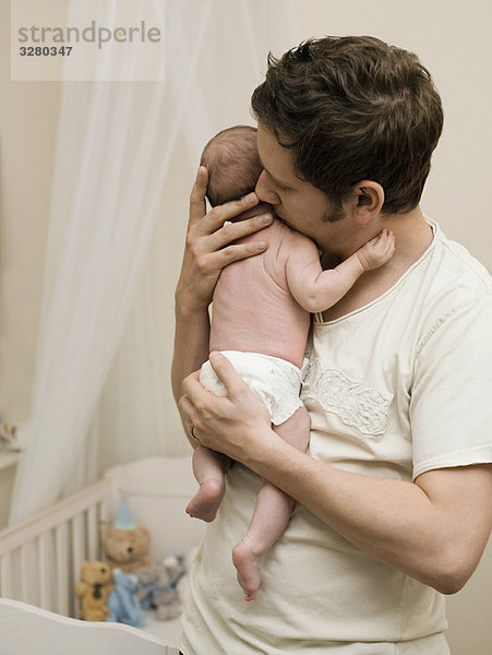 Ein Vater hält sein neugeborenes Baby.