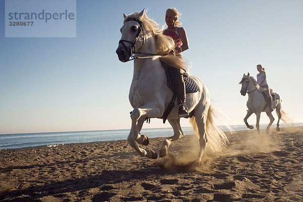 Zwei Frauen auf Pferden am Strand