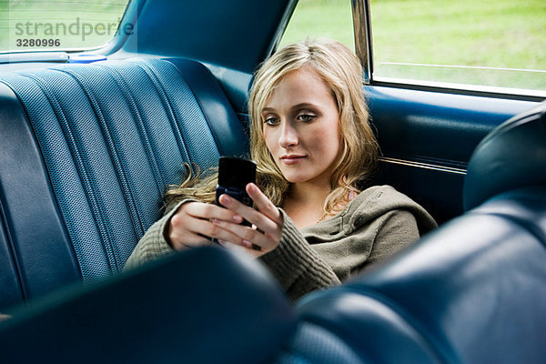 Junge Frau im Auto mit Handy