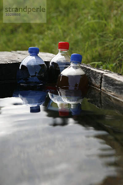 Plastikflaschen mit Soda  die in einen Wassertrog getaucht sind.