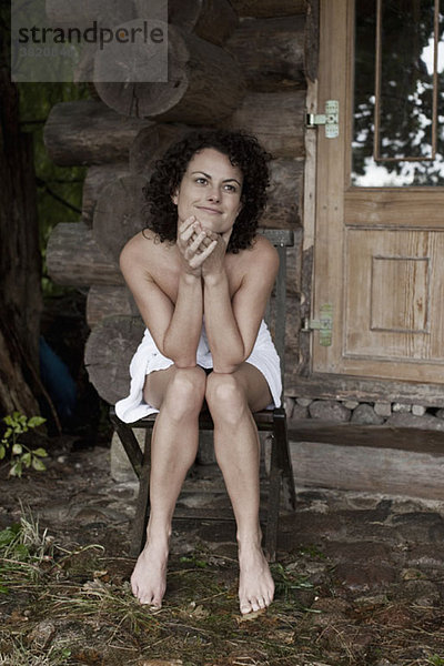 Eine Frau entspannt sich außerhalb der Sauna in einem Wellnessbereich