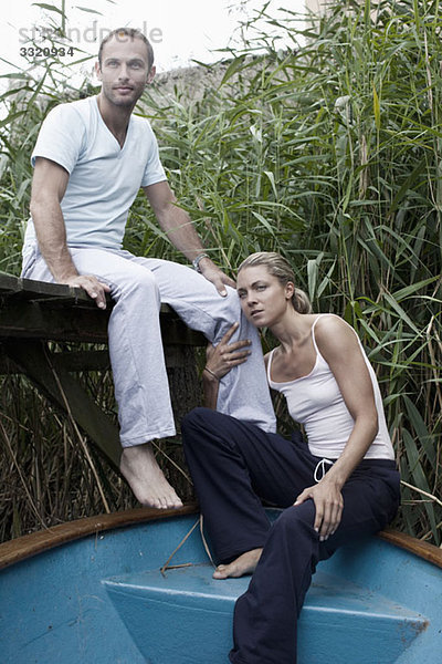 Ein Mann auf einem Steg und eine Frau auf einem Boot sitzend  rührend