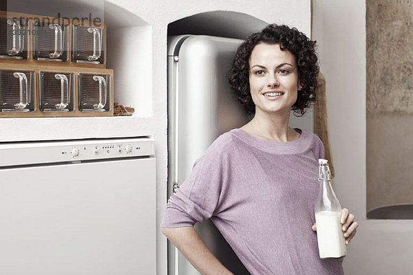 Eine Frau hält eine Flasche Milch in der Küche.