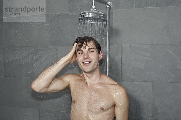 Ein Mann  der unter einer Dusche steht.
