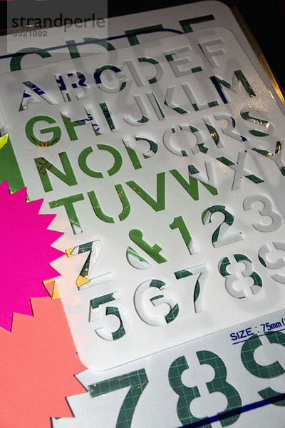Buchstaben- und Zahlenschablonen  farbiges Papier und eine Schneidematte