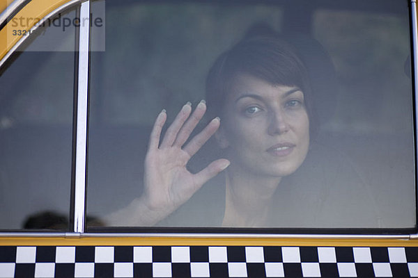 Eine traurige Frau in einem Taxi mit der Handfläche vor dem Fenster.