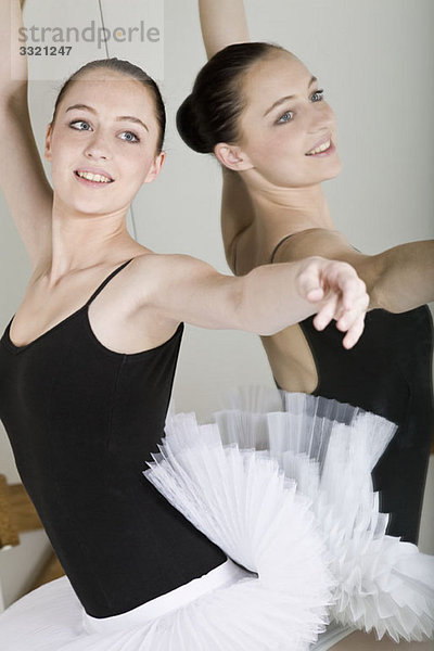 Eine Balletttänzerin  die neben einem Spiegel in einem Ballettstudio posiert.