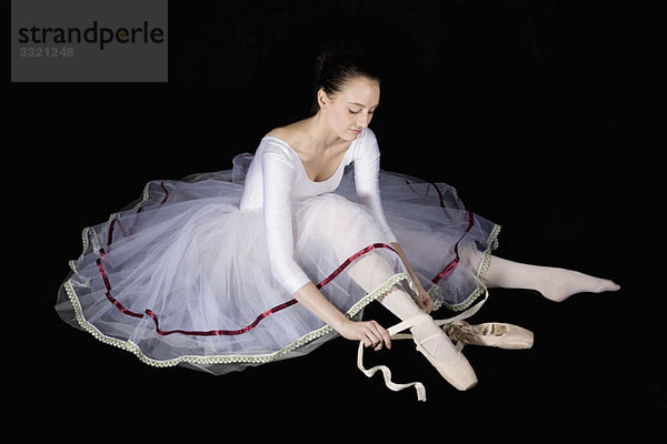 Eine Balletttänzerin  die ihren Spitzenschuh bindet.