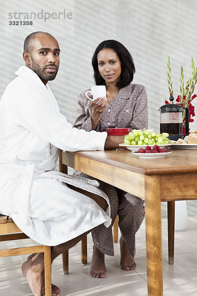 Ein junges Paar sitzt zum Frühstück an einem Tisch.