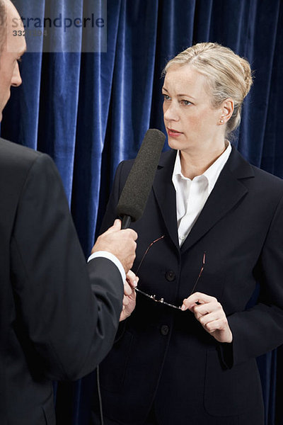 Eine Frau in einem Anzug  die interviewt wird.