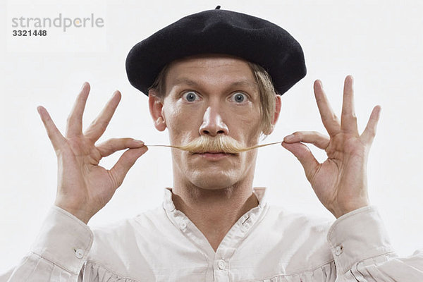 Ein kostümierter Mann  der seinen Schnurrbart verdreht  Portrait