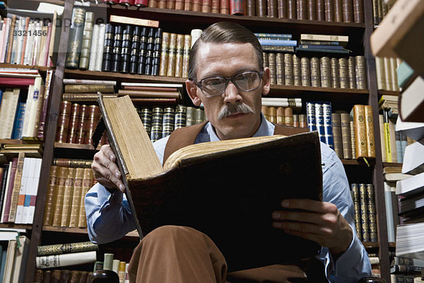 Ein Mann  der ein Buch in einer Buchhandlung liest.