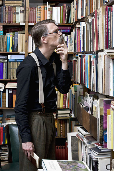 Ein Mann  der Bücher in einer Buchhandlung untersucht.