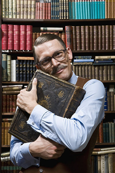 Ein Mann  der ein Buch fest an der Brust hält  glücklich in einer Buchhandlung.