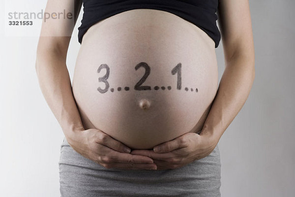 Countdown der Zahlen auf einem schwangeren Bauch  Mittelteil  Fokussierung auf den Bauch