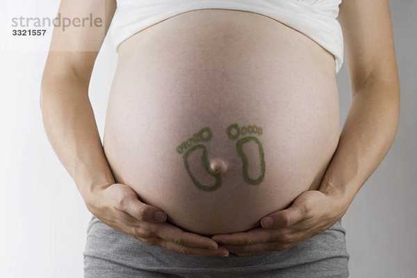 Baby-Fußabdrücke auf einem schwangeren Bauch  Mittelteil  Schwerpunkt Bauch