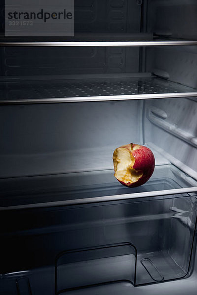 Ein halb gegessener Apfel im leeren Kühlschrank