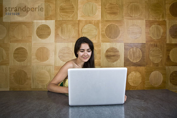 Eine junge Frau sitzt an einem Marmortisch mit einem Laptop.