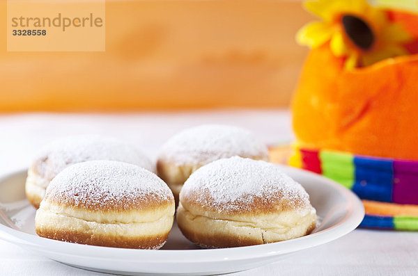 Krapfen auf einem Teller vor einem bunten Hut  Close-up