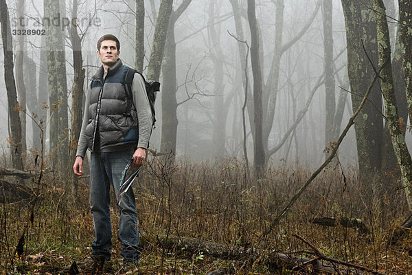 Ein männlicher Wanderer  der in einer nebligen Waldöffnung steht.