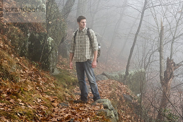 Ein männlicher Wanderer erkundet einen nebligen Wald