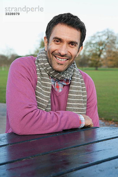 Ein erwachsener Mann  der an einem Tisch im Dulwich Park sitzt.