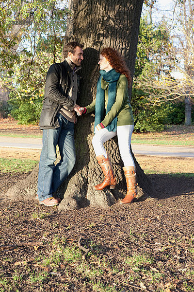 Ein Paar steht von Angesicht zu Angesicht neben einem Baum.