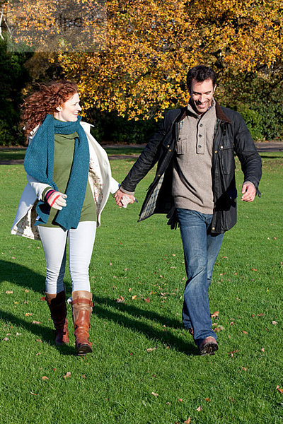 Ein mittleres erwachsenes Paar hält sich im Dulwich Park an den Händen.