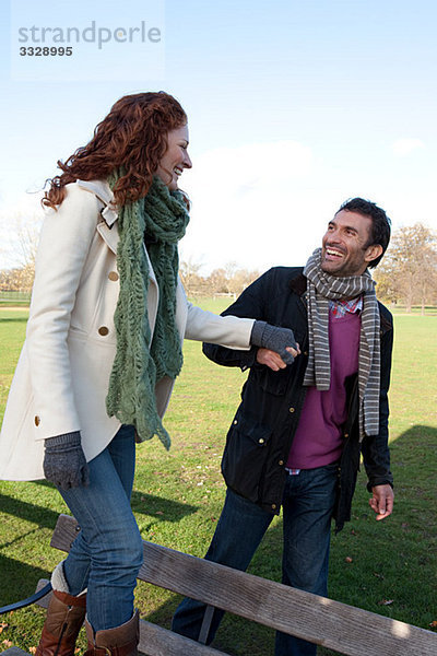 Eine Frau  die auf einer Parkbank läuft  während sie mit ihrem Partner Händchen hält.