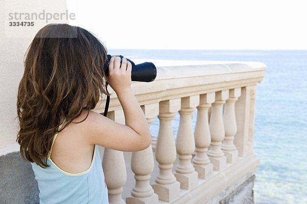 Mädchen mit Fernglas mit Blick aufs Meer