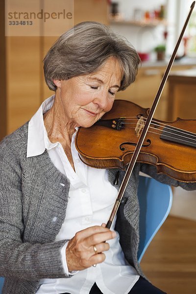 Alte Frau beim Stimmen von Violine