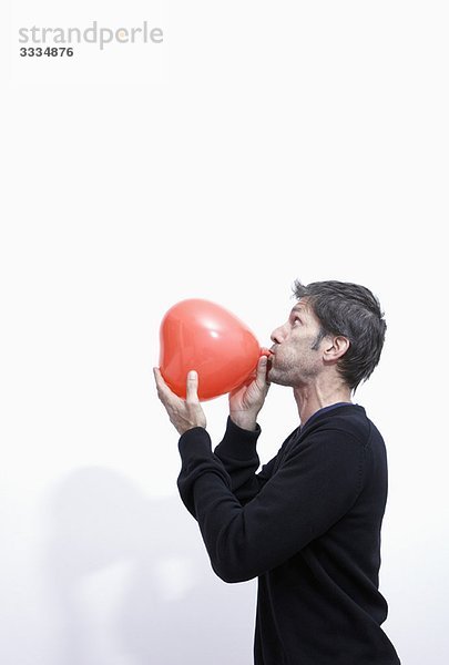 Mann beim Aufblasen eines Herzballons