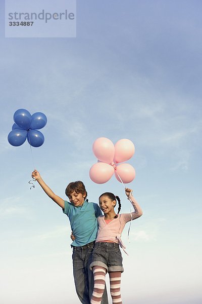 zwei Kinder lachen mit Luftballons