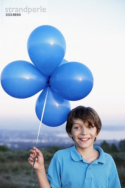 lächelnder Junge mit Heliumballons